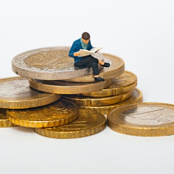 Figurine man sitting on stack of coins